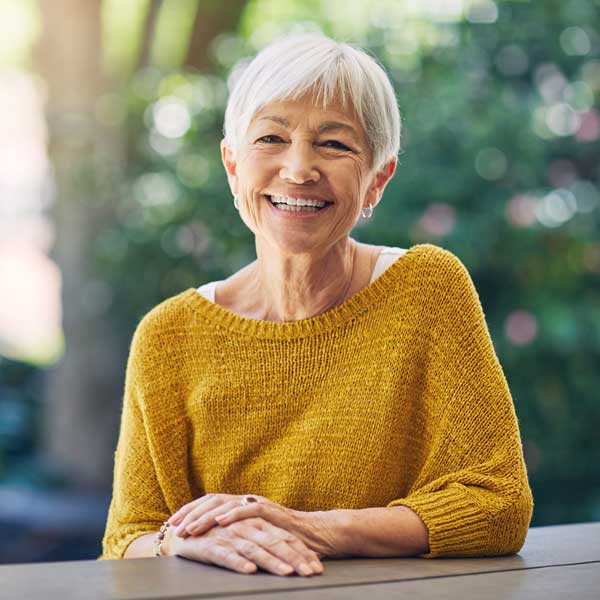 Shot of a happy senior woman sitting at a table in her backyard