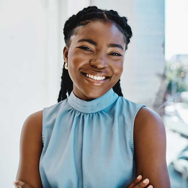 Confident young black businesswoman standing at a window in an office
