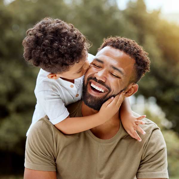 father laughing while young son kisses his cheek