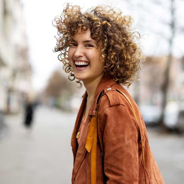 Beautiful woman walking outdoors looking behind and laughing
