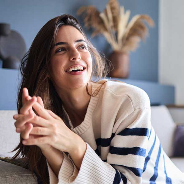 Beautiful woman smiling brightly while lounging on her comfortable sofa